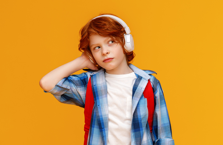 Modern schoolboy listening to music in headphones